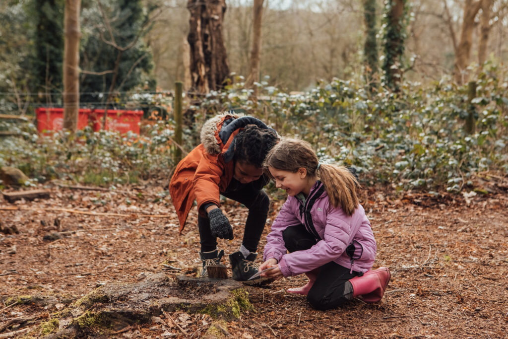 Children picking up stick in woodland